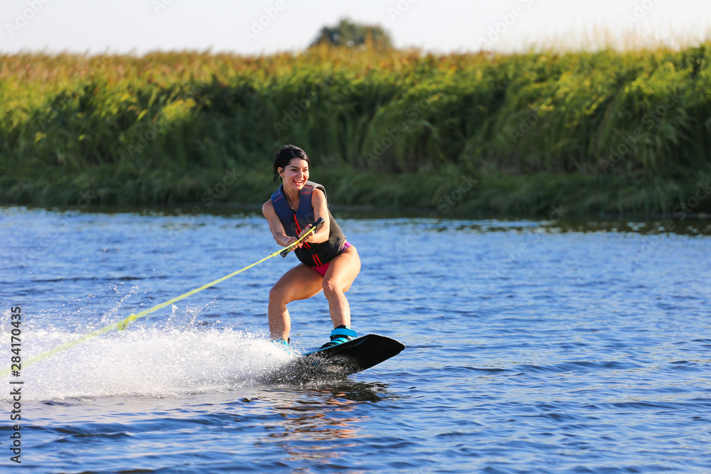 Happy girl riding on wakeboard at sunny day , smiling and happy Happy girl riding on wakeboard at sunny day , smiling and happy