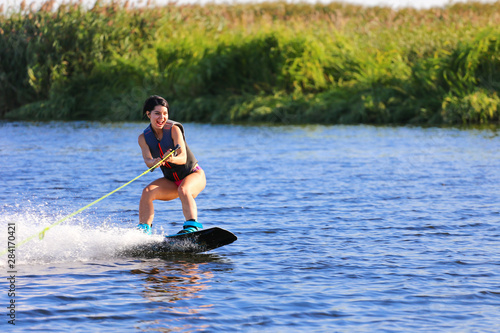 Happy girl riding on wakeboard at sunny day , smiling and happy 