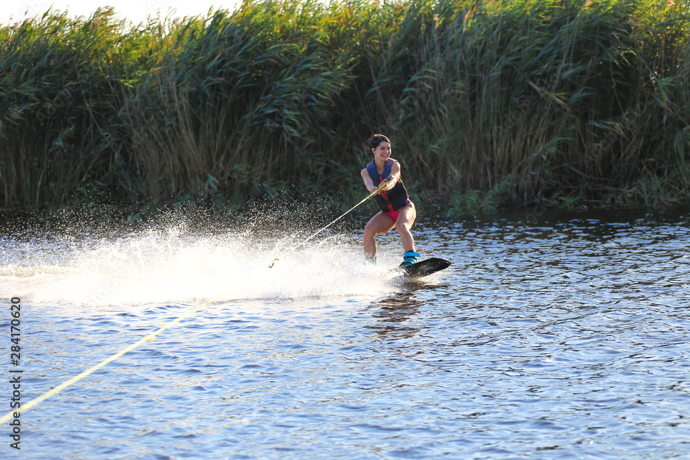 Happy girl riding on wakeboard at sunny day , smiling and happy Happy girl riding on wakeboard at sunny day , smiling and happy
