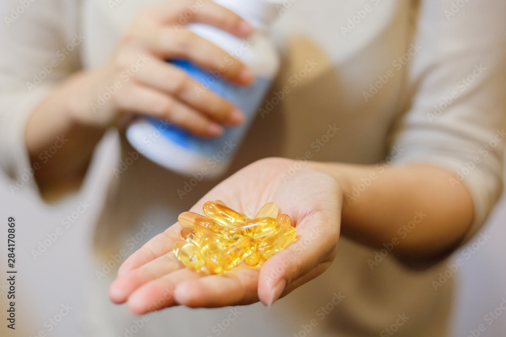 Close up of beautiful woman with fish oil capsules from jar to hand. Sport, healthy lifestyle, medicine, nutritional supplements, people concept and healthy concepts. Close up of beautiful woman with fish oil capsules from jar to hand. Sport, healthy lifestyle, medicine, nutritional supplements, people concept and healthy concepts.