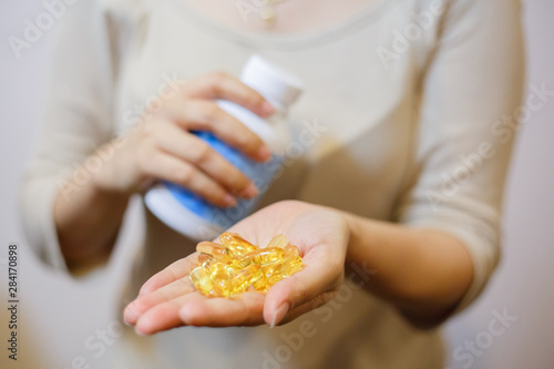 Close up of beautiful woman with fish oil capsules from jar to hand. Sport, healthy lifestyle, medicine, nutritional supplements, people concept and healthy concepts.