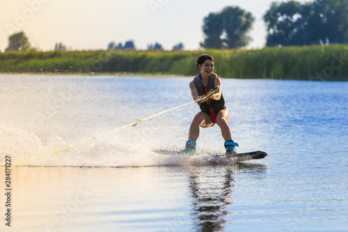 Happy girl riding on wakeboard at sunny day , smiling and happy 
