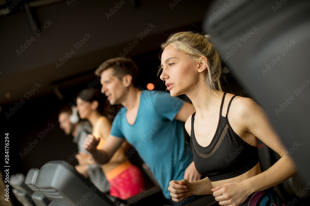 Young people using threadmill in modern gym Young people using threadmill in modern gym