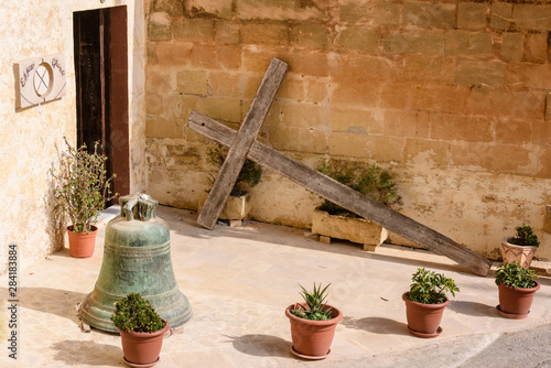 A large wooden cross lies propped up against a wall outside a house in Gozo, Malta.