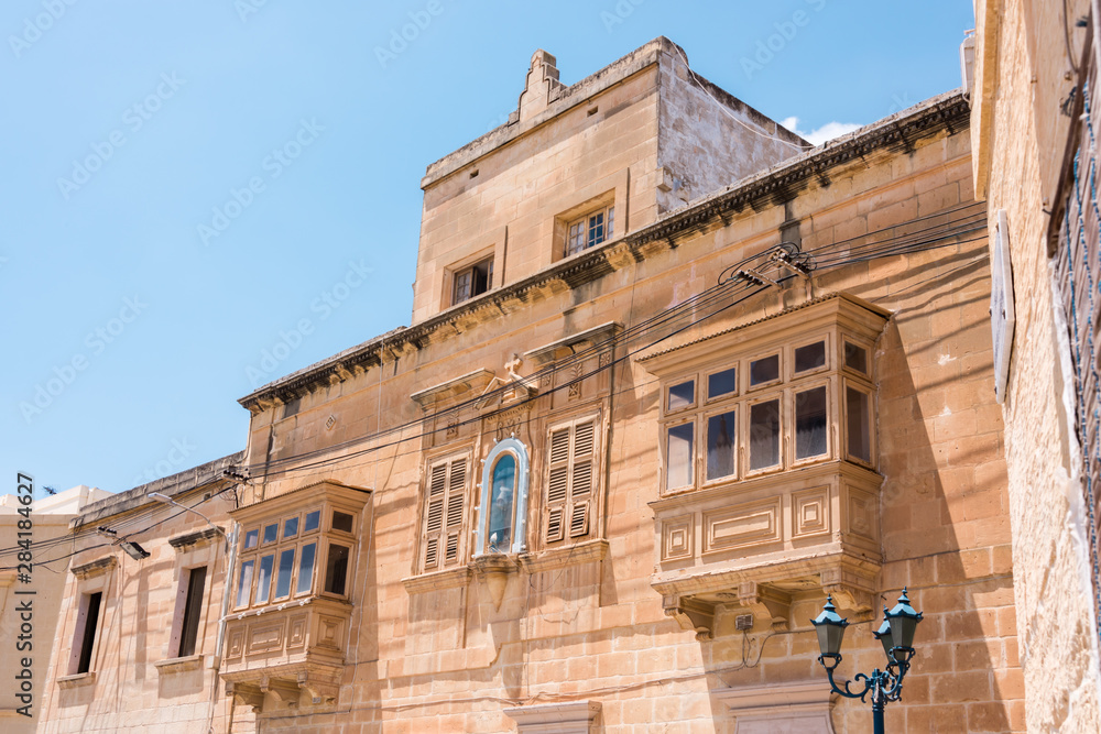 Traditional wooden balconies on either side of a Marian shrine on a building in Ghajnsielem, Gozo, Malta