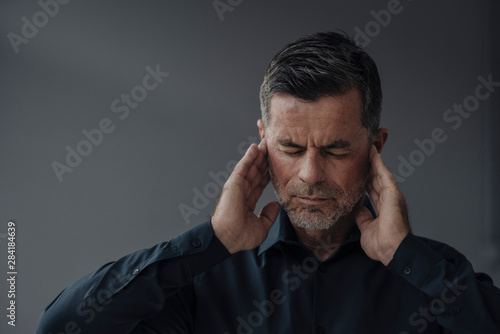 Portrait of mature businessman having earaches photo