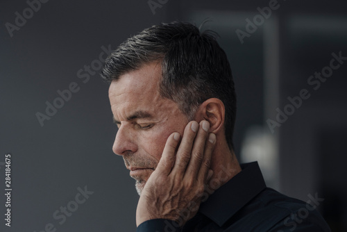 Portrait of mature businessman having earaches photo