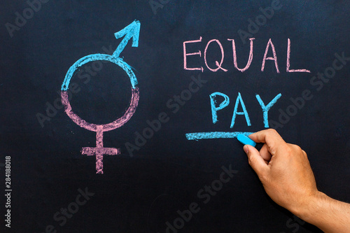 The pay gap and the symbol of gender equality are depicted on the chalkboard. Man's hand with chalk. The concept of gender equality.