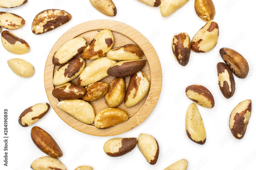 Lot of whole single unshelled brazil nut on bamboo plate flatlay isolated on white background Lot of whole single unshelled brazil nut on bamboo plate flatlay isolated on white background