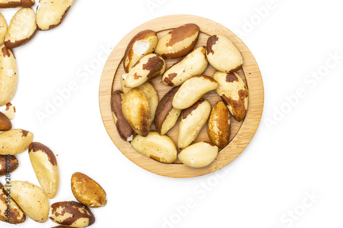 Lot of whole unshelled brazil nut on bamboo plate flatlay isolated on white background