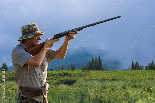 Hunter with a hat and a gun in search of prey in the steppe against the backdrop of a mountains