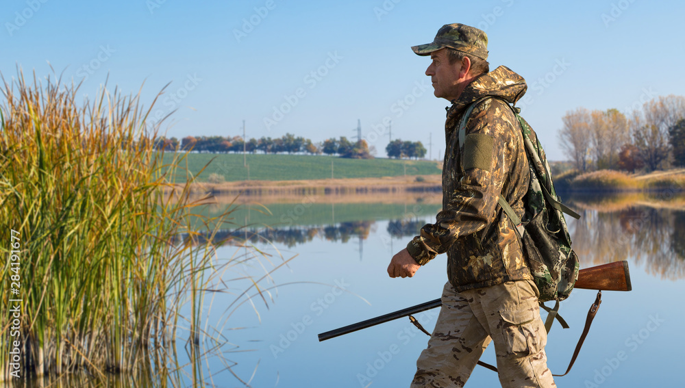 Hunter with a german drathaar and spaniel, pigeon hunting with dogs against the backdrop of a beautiful evening lake. Hunter with a german drathaar and spaniel, pigeon hunting with dogs against the backdrop of a beautiful evening lake.