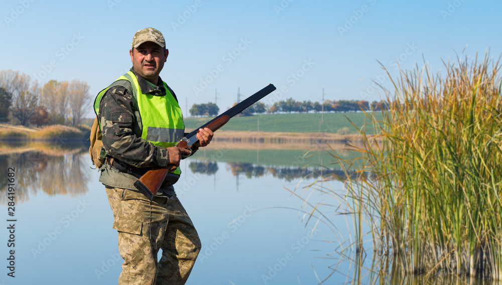 Hunter with a german drathaar and spaniel, pigeon hunting with dogs against the backdrop of a beautiful evening lake.