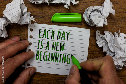 Word writing text Each Day Is A New Beginning. Business concept for Every morning you can start again Inspiration Hand hold green pen and words on white page paper lobs around on wooden desk photo