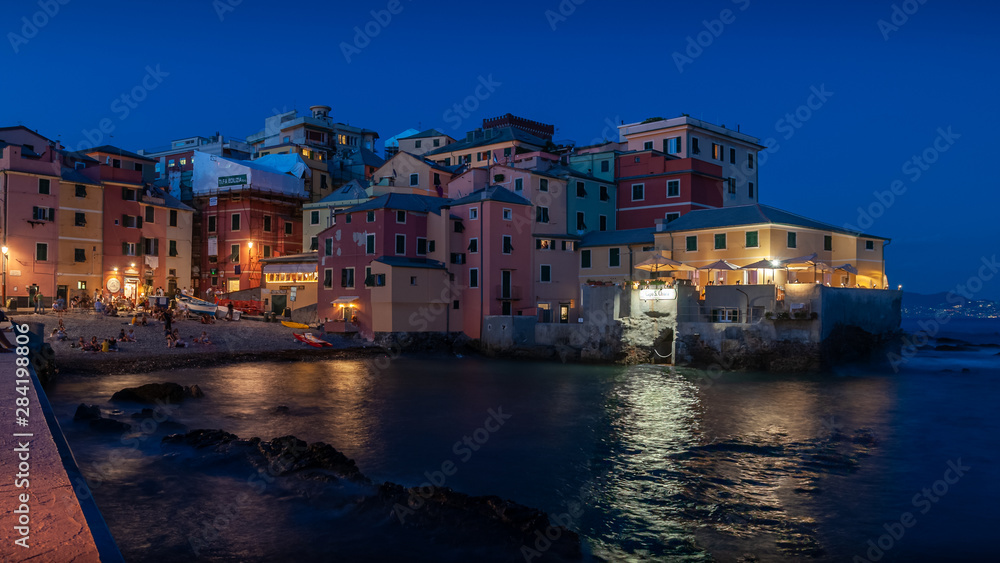 Genoa, Italy. Incredible night view of the ancient fishing village of Boccadasse overlooking the sea. Reflections of lights on the waters of the sea