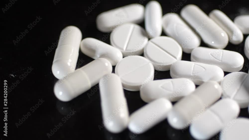 Slider Shot of White Pills and Tablets on black background Slider Shot of White Pills and Tablets on black background