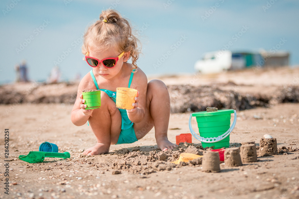 Adorable toddler girl playing on white sand beach Adorable toddler girl playing on white sand beach
