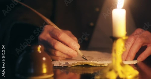 close shot of 1700s man writing with a quill pen