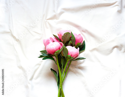 Peony flowers on the white cotton blanket. Concept floral top view 