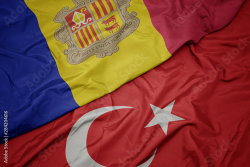 waving colorful flag of turkey and national flag of andorra.