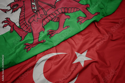 waving colorful flag of turkey and national flag of wales.