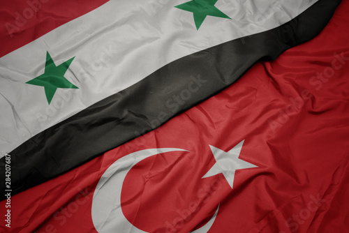 Tela waving colorful flag of turkey and national flag of syria.