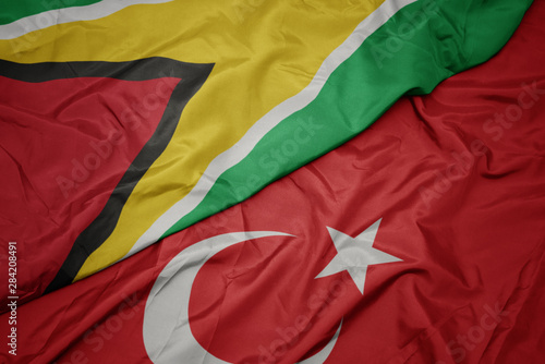 waving colorful flag of turkey and national flag of guyana.