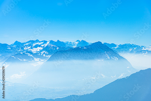 Majestic unique misty blue alpine skyline aerial view panorama of iced Swiss Alps and blue sky  taken from inside a cable lift cabin at mount Rigi Switzerland.
