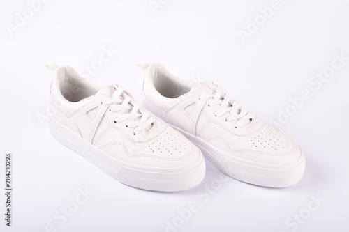 A pair of white sneakers on the white background
