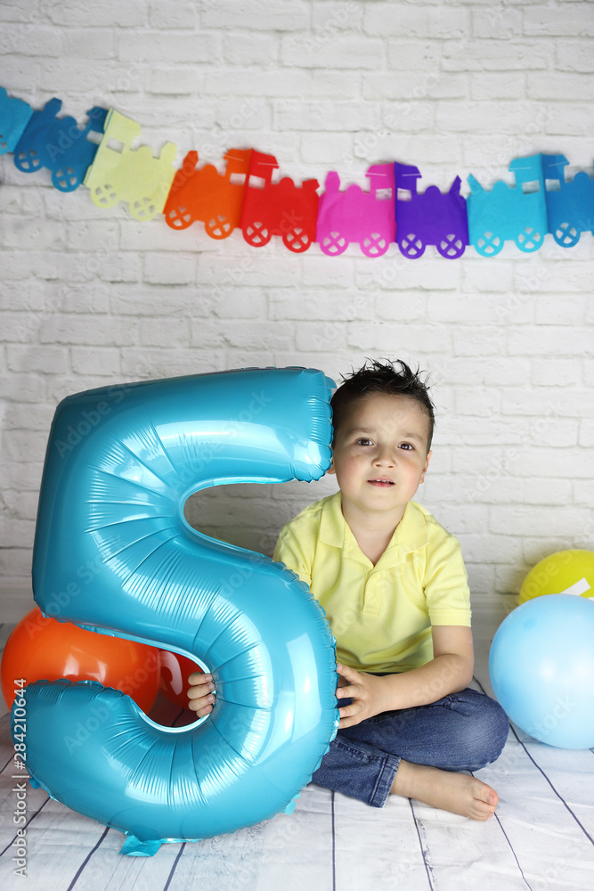 niño de 5 años en su fiesta de cumpleaños con globos y guirnaldas foto de  Stock