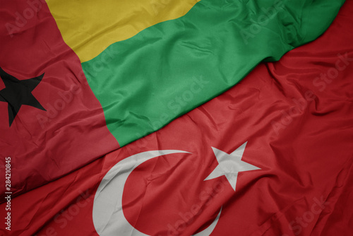 waving colorful flag of turkey and national flag of guinea bissau.