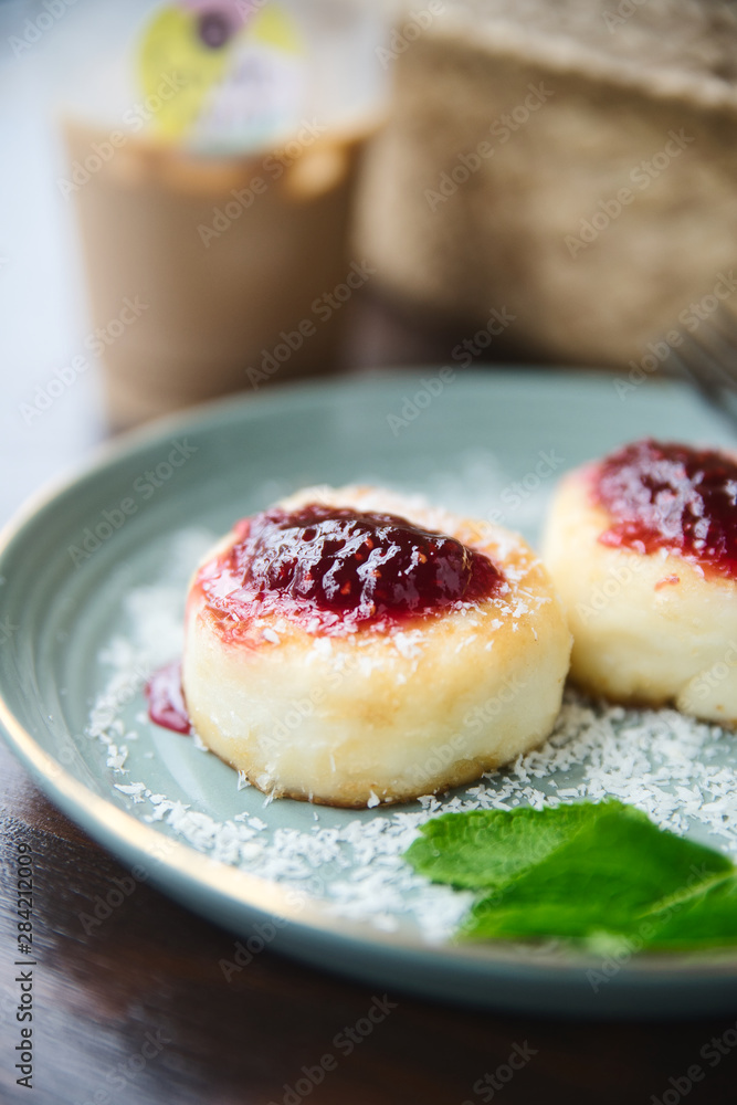 Cheesecakes with raspberry jam and mint leaves served with a cup of ice latte