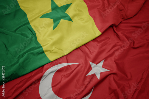 waving colorful flag of turkey and national flag of senegal.