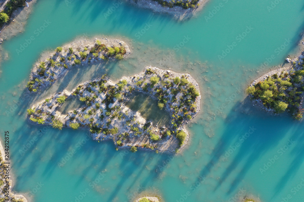 Islands in an turquoise quarry pond with trees Islands in an turquoise quarry pond with trees