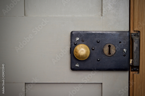 Vintage Victorian rim lock on a grey door with brass knob