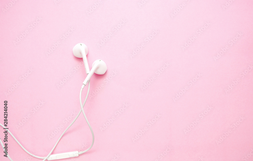 white headphones on pink background with copy space