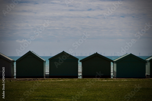 seascape of beach huts with wind turbines on the horizon