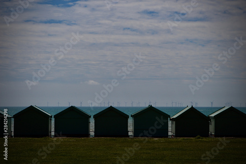 seascape of beach huts with wind turbines on the horizon © jk daylight