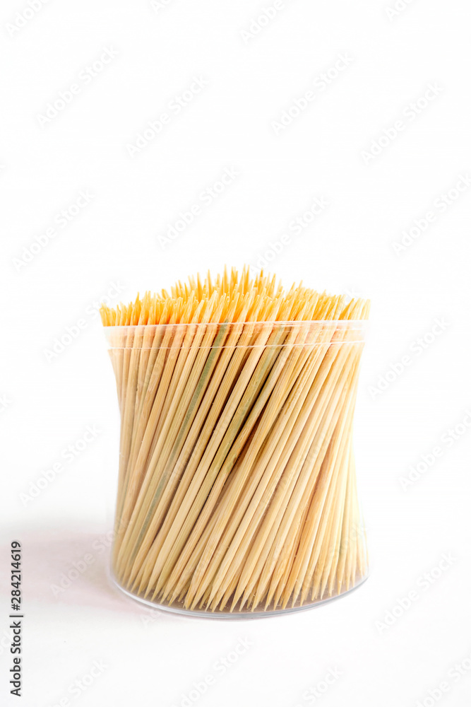 Bamboo toothpicks in a plastic storage box on white background. Vertical view, selective focus