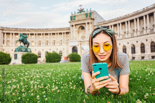 Photography Young asian woman using her smartphone for internet surfing lying on a green gra