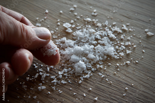 Sea salt on an oak table being picked up by the chef