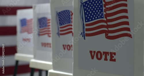 CU small crane move from side, pushing in to row of voting booths at polling station. US flag in background. Slow motion 4K 60fps