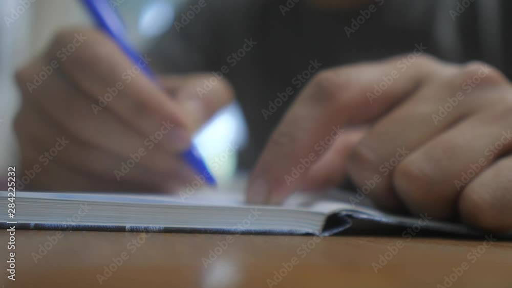 man writes in notebook. man's hand writing in a notepad. concept lifestyle business education. man makes notes in a notebook that lies on the table man writes in notebook. man's hand writing in a notepad. concept lifestyle business education. man makes notes in a notebook that lies on the table