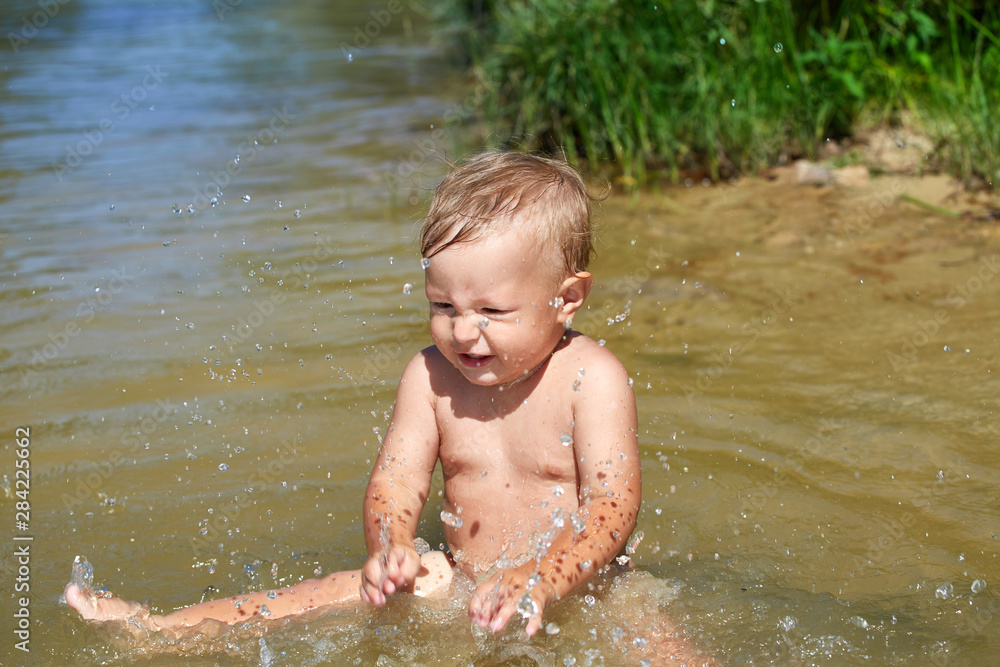 Cute baby plays in the water near the shore Cute baby plays in the water near the shore