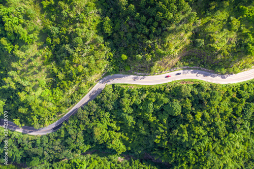Aerial view of countryside road passing through the tropical rainforest and mountain in SouthEast Asia.
