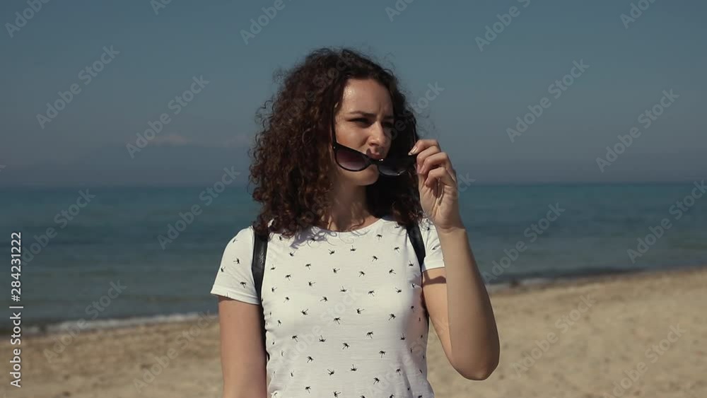 Portrait of beautiful young woman take of sunglasses and watching around on the beach on sunny day Portrait of beautiful young woman take of sunglasses and watching around on the beach on sunny day