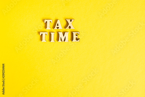Economic phrase Tax Time isolated on yellow paper background with copy space.