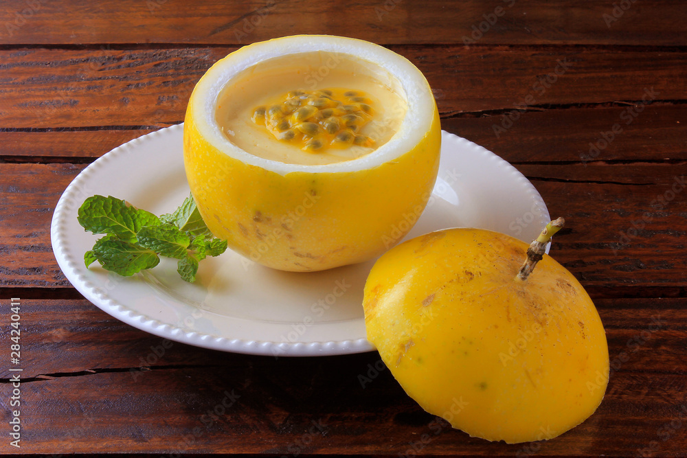 dessert Passion fruit mousse in the peel of the fruit, on plate over rustic wooden table