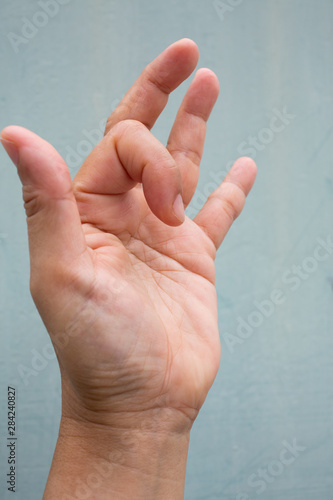 Trigger Finger lock on index finger of woman's side left hand, Suffering from pain, On Blue-grey colour background,  Close up & Macro shot, Office syndrome, Health care concept photo