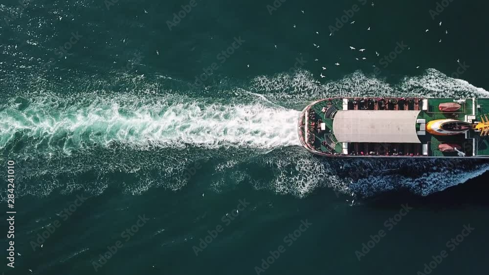Beautiful trail on the sea surface behind of the cruise ship. Her engine roaring at full speed leaving wake water on the Bosphorus Sea. Aerial top down view of Water foam trace behind the ferryboat
